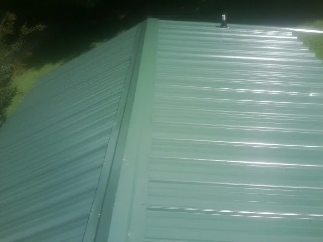 New green metal panels meeting at the ridge of a roof — Flat Roof Repair work by our crew in Rachel