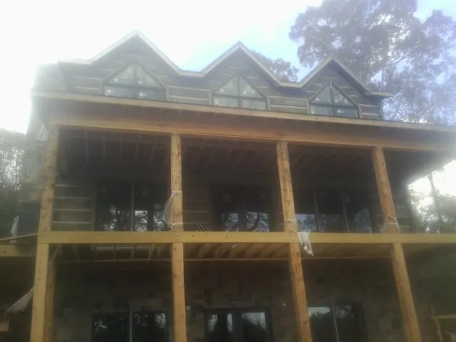 Dormers and porch framing on a large log home under construction — Roof Coating work by our crew in Rachel