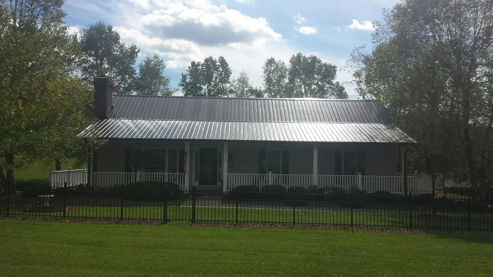 Gray metal roof on a brick ranch with a full width front porch — Gutter Guard Installation work by our crew in Rachel