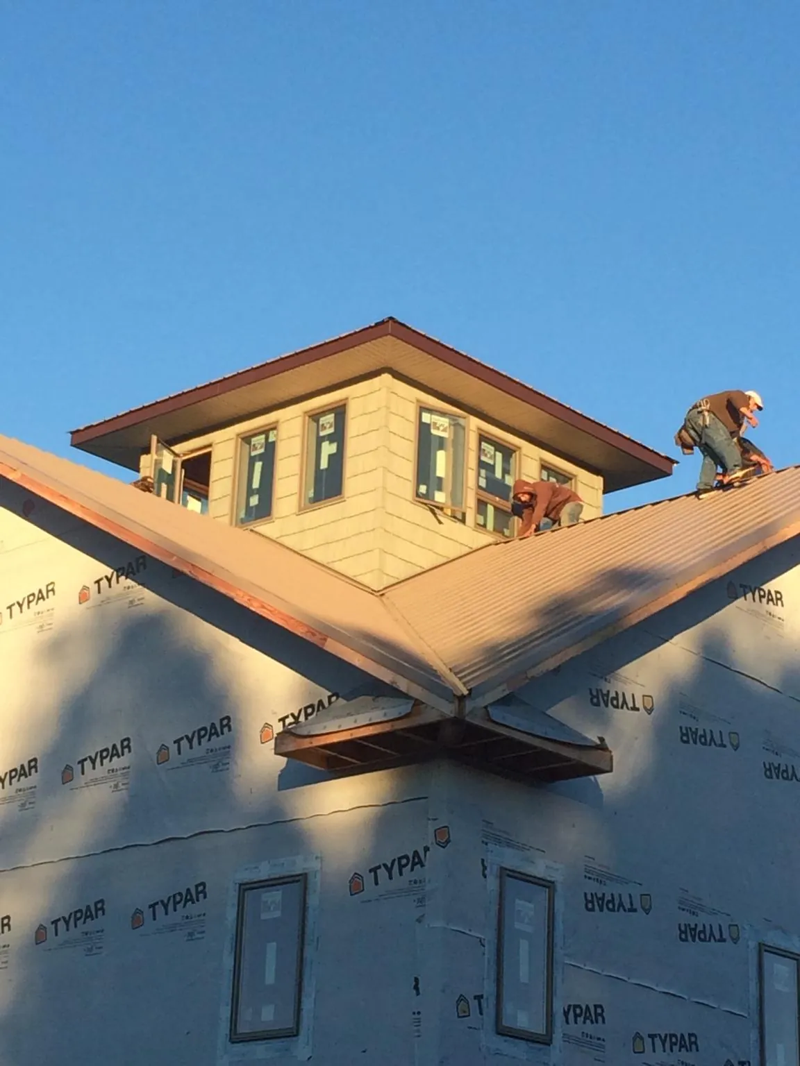 Roofers working around a rooftop cupola on a new metal roof at sunset — Roof Waterproofing in Rachel by Roofing Brothers